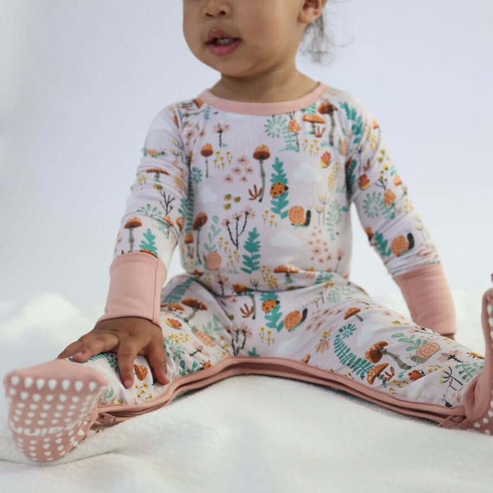 Child sitting while wearing a Rainn Bamboo Fern Crescent Zipp Jammies on a white background