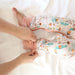 Detail of parent putting the Rainn Bamboo Fern Crescent Zipp Jammies foot covers on their child on a white background