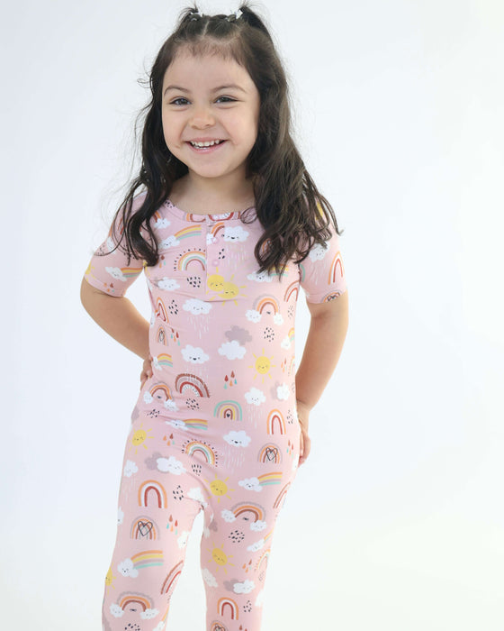 Child smiling while wearing a Rainn Bamboo Rainnbow Pull Up Romper on a white background